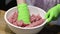 Close up view of female hands in green gloves working with chopped meat in white bowl.