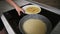 Close up view of female hands pouring pancake mix in a frying pan and spreading it around. Homemade food. Slowmotion