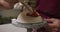 Close up view of female potter wearing apron painting pot on potters wheel at pottery studio