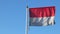 Close-up view of flag of Indonesia waving in the wind on a blue sky background without clouds, two horizontal stripes, where the t