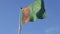 Close-up view flag of Turkmenistan waving in the wind on a blue sky background without clouds, dark green leaf with five white fiv