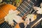 Close-up view of a fragment of acoustic classical guitar with fall maple leaf on wooden background. Autumn concept
