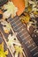 Close-up view of a fragment of acoustic classical guitar with fall maple leaf on wooden background. Autumn concept