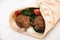 Close up view of fresh falafel balls in pita with vegetables and sauce on white background.