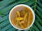 Close up view of fresh Kerala sambar in a white saucer green coconut palm leaves background