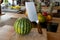 Close-up view of fresh water melon and a cleaver standing on a cooking island
