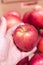 Close up view of fruits shelf in supermarket. hand taking red apples in the store. male hand taking fruit from a shelf