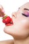 Close up view of girl with red lips eating strawberry