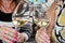 Close-up view of glasses of cold wine in the hands of the women sitting at the table of a summer cafe.