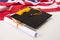 Close-up view of graduation mortarboard, diploma and us flag on grey