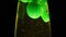 Close up view of green lava lamp isolated on black background. Concept. Unusual lamp with dim light and moving green