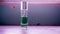 The close up view of the green perfume liquid in a glass bottle with light flare on the background