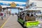 Close up view of a green Tram car filled with tourists riding on the Atlantic City Boardwalk near the Hard Rock Hotel sign