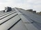 close up view of grey folding roof and chimney on waterproofing layer of house under construction