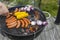 Close up view of grilling sausages, corn and onion outdoors on summer day.