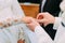 Close-up view of the hand of the groom putting the wedding ring on the finger of the bride.