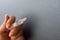 Close up view of hand holding a syringe and a needle with a drop on dark gray background. Flu shot or drug abuse concept.