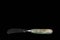 Close up view of handmade butter knife on black background.