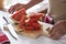 Close-up view of the hands of an elderly person and a wooden cutting board with slices of freshly cut watermelon - healthy and