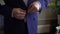 Close-up view of the hands of the groom buttoning the wedding jacket.