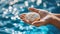 Close up view of hands holding a shell with a sparkling reflection from the water