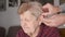 Close-up view of hands inserts hearing aid device to the elderly woman\'s ear