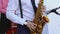 Close up view of the hands of a male saxophonist playing a tenor saxophone in an orchestra.