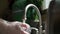 Close up view of Hands in orange gloves wash dishes in the kitchen.