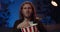 Close up view of handsome man with long hair watching sport and eating popcorn. Millennial hipster guy sitting on sofa