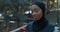 Close up view of happy woman using smartphone and drinking water from plastic bottle. Female muslim person in hijab