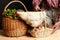 Close up view of hen standing on basket full of straw and fresh-laid eggs