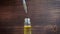 Close-up view of holding the pipette full with essential oil above the bottle and droplets are falling inside