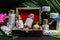 Close up view of homeopathic pills bottles in wooden old box with pink flower bud, wild fruit, burlap and green leaf on dark