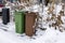 Close up view of house mail post box and waste and recycling containers on snowy bushes background.