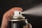 Close-up view of human hand and spray bottle isolated on black