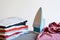 Close up view of iron clothes on ironing board with stack of ironed shirts