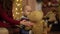 Close up view of little cute child playing with big teddy bear at home. Mother sitting near the son holding shaking toy