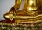 Close up view of the low hand golden buddha statue sitting meditation with copy space and sunlight