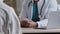 Close-up view male unknown doctor therapist man in white medical uniform sit at desk consult patient complaints give