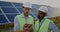 Close up view of male worker in hard helmet standing at solar farm and looking at tablet screen. Two men engineer in