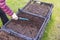 Close up view of man loosen soil with a rake in garden bed in pallet collar..