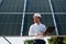 Close up view of man\'s hand that is holding light bult in front of solar panel