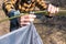 Close up view man in yellow shirt sets up tent in mountains in springtime