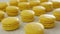 Close-up view of many rows of yellow lemon macarons macaroon on white background. Classical French dessert.