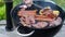 Close up view of men grilling meat steak, corn, sausages and onions outdoors on a summer day. Healthy food concept.