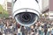 Close-up view of a modern security camera keeping watch over a city street crowd. Generative AI digital illustration