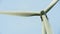 Close-up view of a modern windmill against a blue sky. The white blades of the wind turbine. Clean and renewable energy