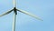 Close-up view of a modern windmill against a blue sky. The white blades of the wind turbine. Clean and renewable energy