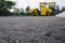 Close up view on the new asphalt road on which road roller is working. Construction site