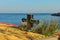 Close-up view of new shiny mooring bollard overgrown with weeds. Unused marina. Blurred sea with the sky at the background.